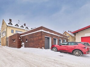 A wooden building with a garage, a red car parked in front, and a snow-covered ground. - Vysoké nad Jizerou by Interhome (Vysoké nad Jizerou)