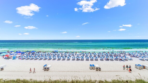 A beach with rows of blue and white sunbeds and umbrellas, a sandy beach, and the ocean in the background. - Last min Sept 12 - 14th! 2nd floor! (Panama City Beach)