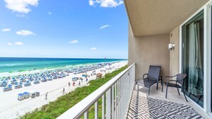 A balcony with a view of a beach, a chair, and a patterned rug. - Last min Sept 12 - 14th! 2nd floor! (Panama City Beach)