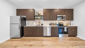 A modern kitchen with dark wooden cabinets, stainless steel appliances, and a light-colored countertop. - Bright New 2BR in Tekamah at Tiger Town (Tekamah)