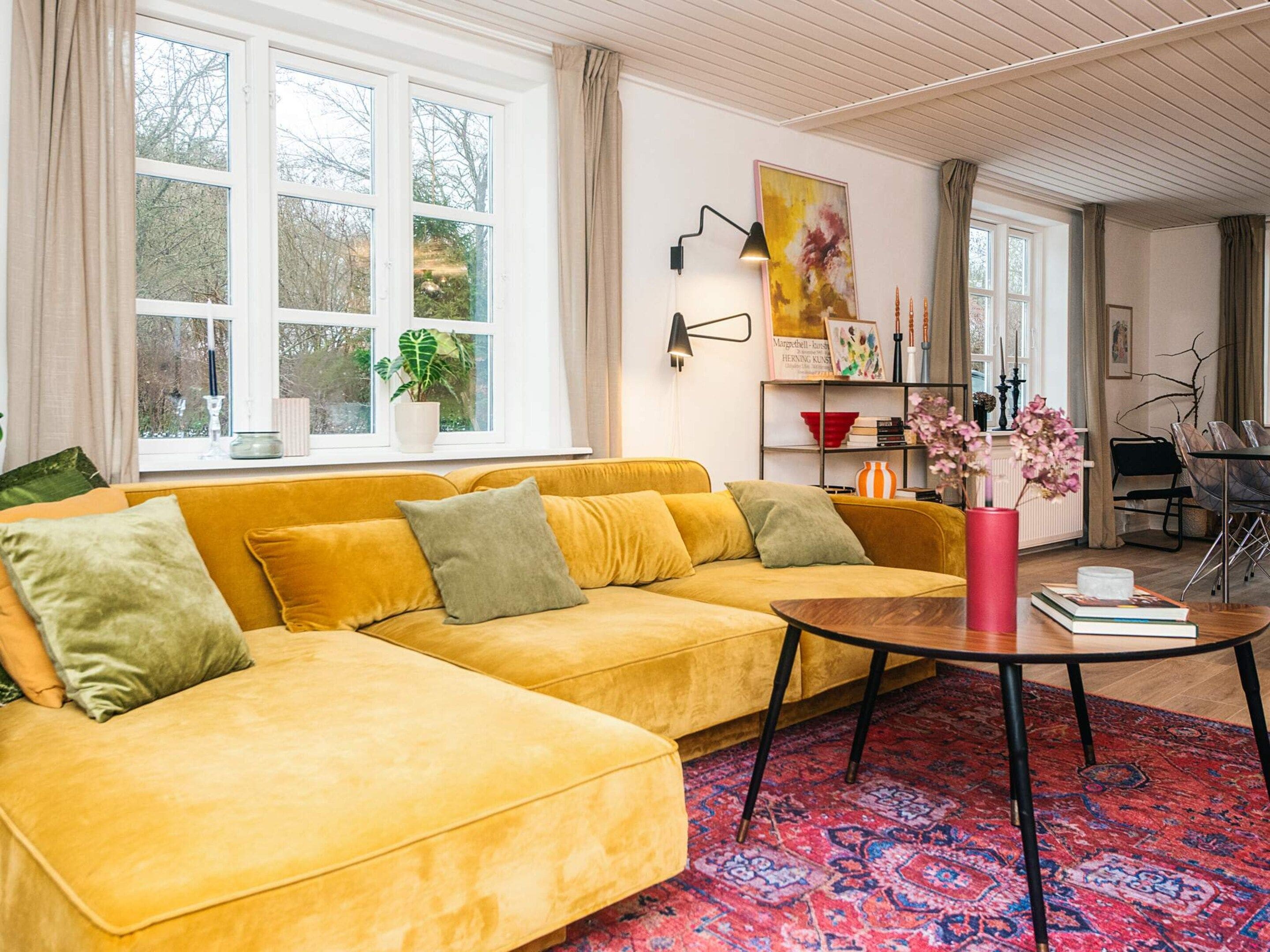 Un soggiorno con un divano giallo, un tavolino da caffè e un tappeto decorato.