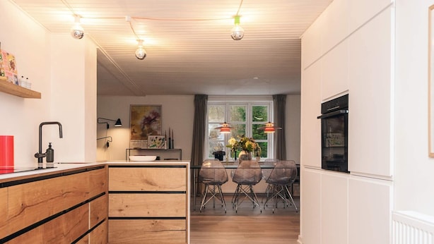 Et moderne køkken med træskabe, en central ø og et spiseområde med stole.