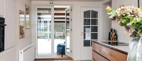 A modern kitchen with a wooden floor, white cabinets, and a large window.
