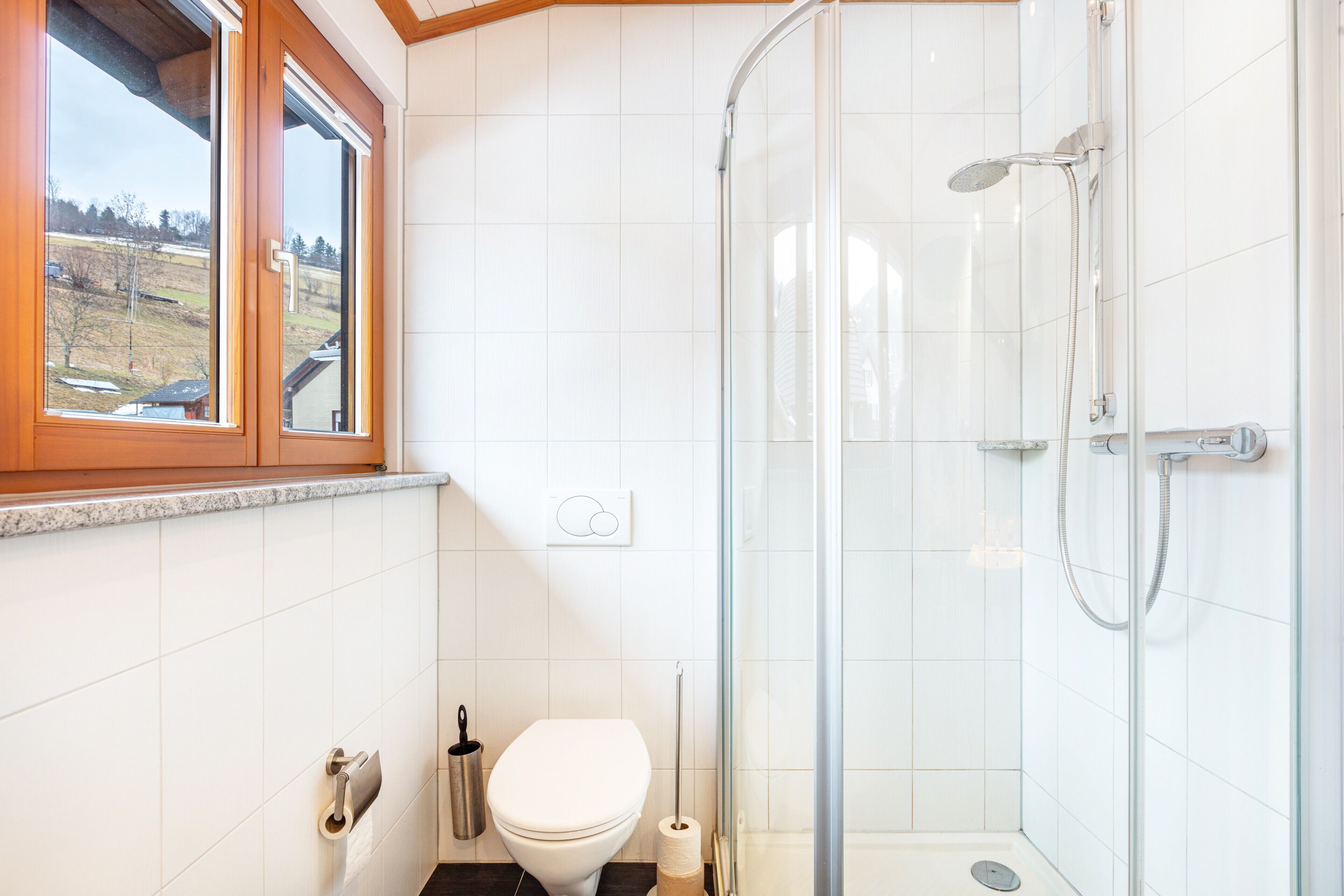 Une salle de bain avec des toilettes, une douche et une fenêtre.