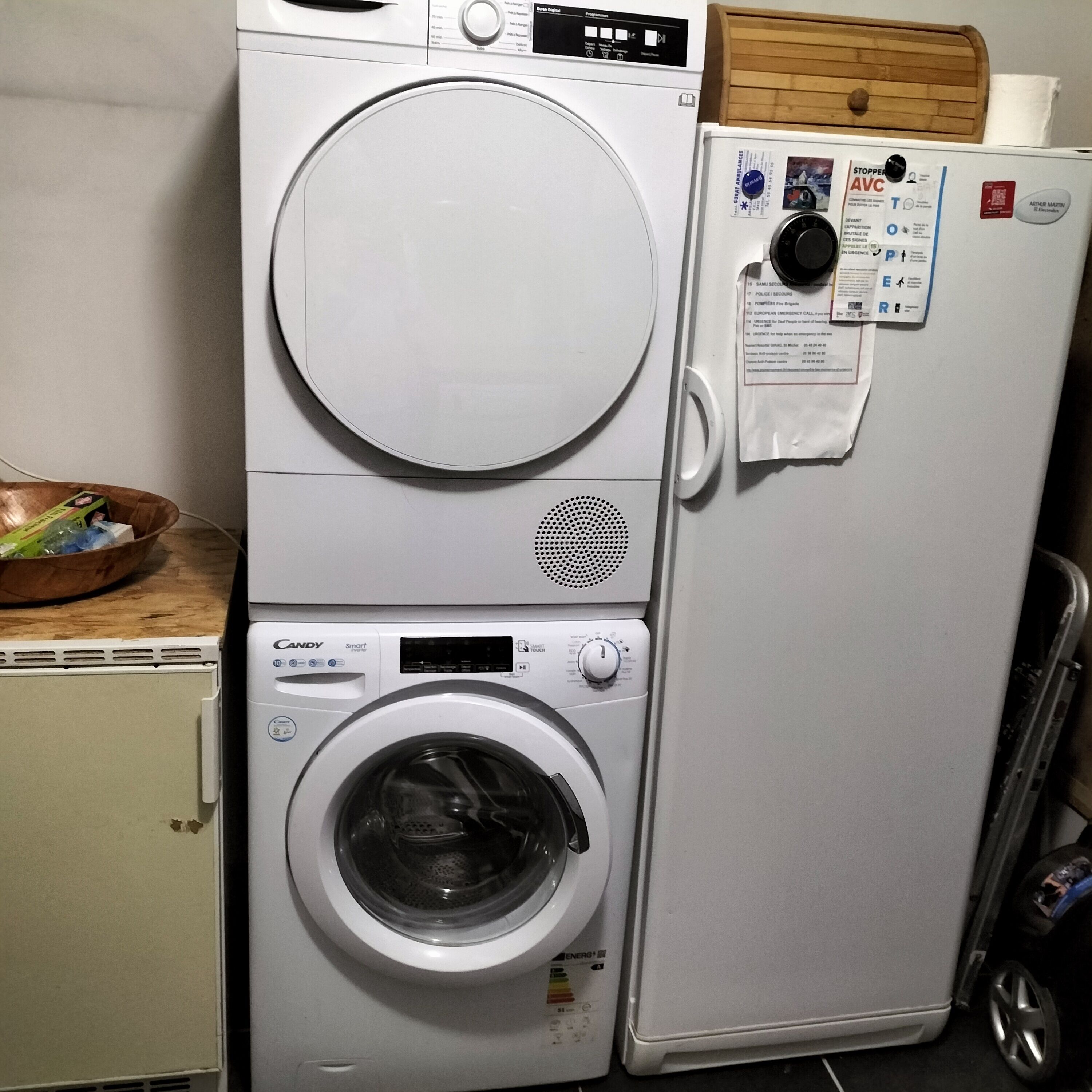 Een kleine wasruimte met een voorlader wasmachine en droger, een klein kastje en een houten dienblad erboven.
