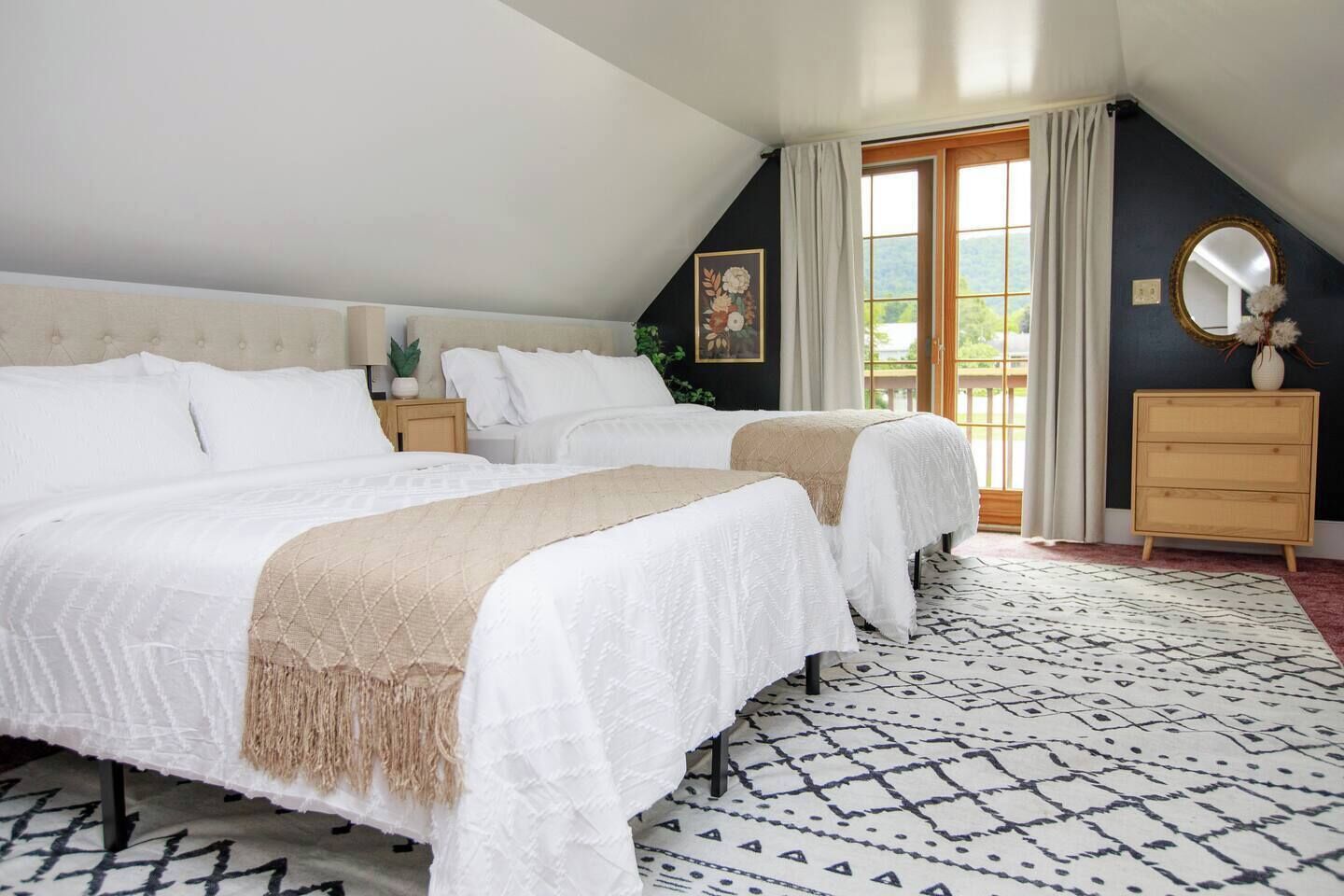 Une chambre avec deux lits, une commode, un miroir et une fenêtre avec des rideaux.