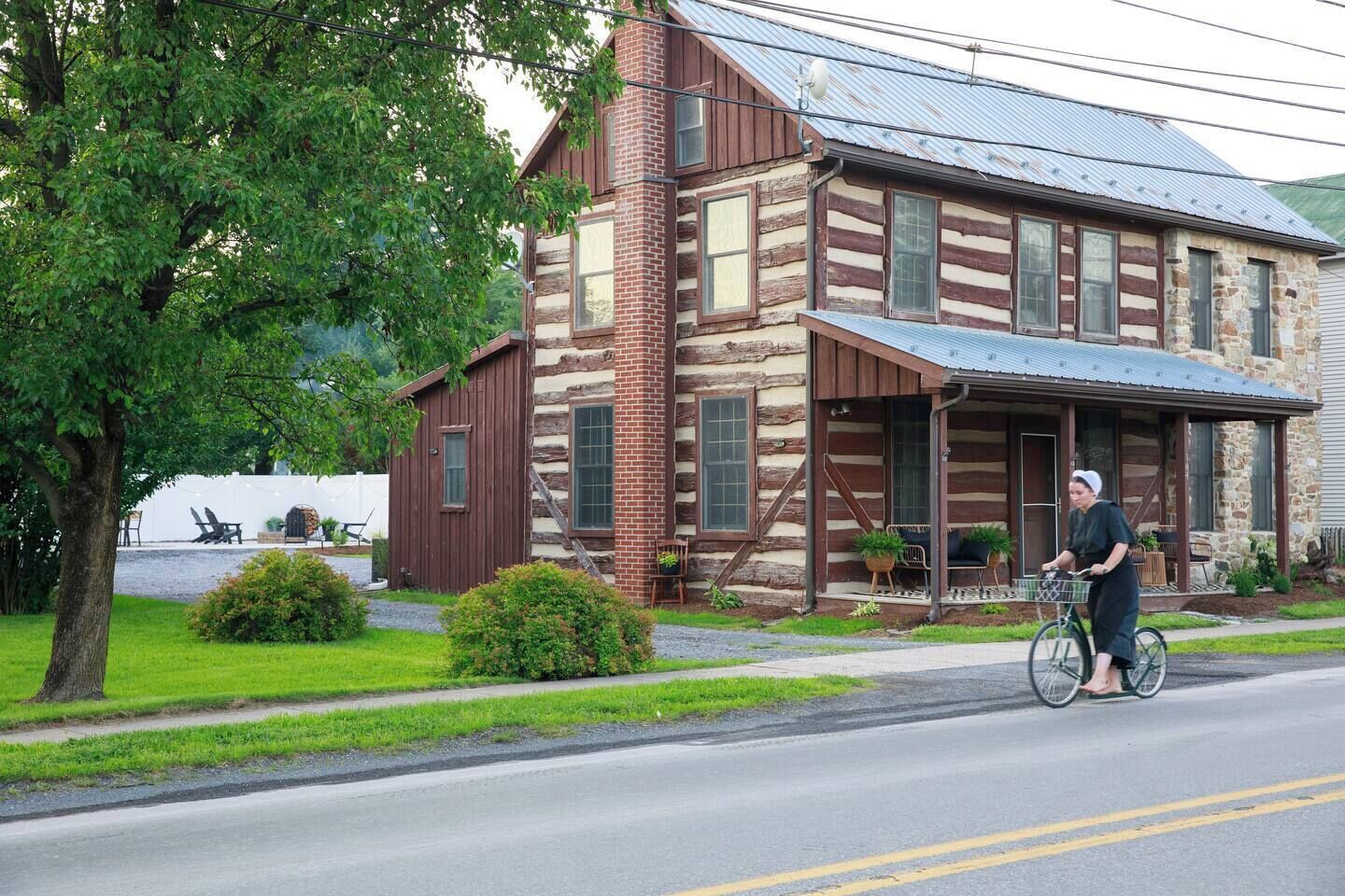 Een blokhut met een veranda, een fietser en een gazon met een boom.