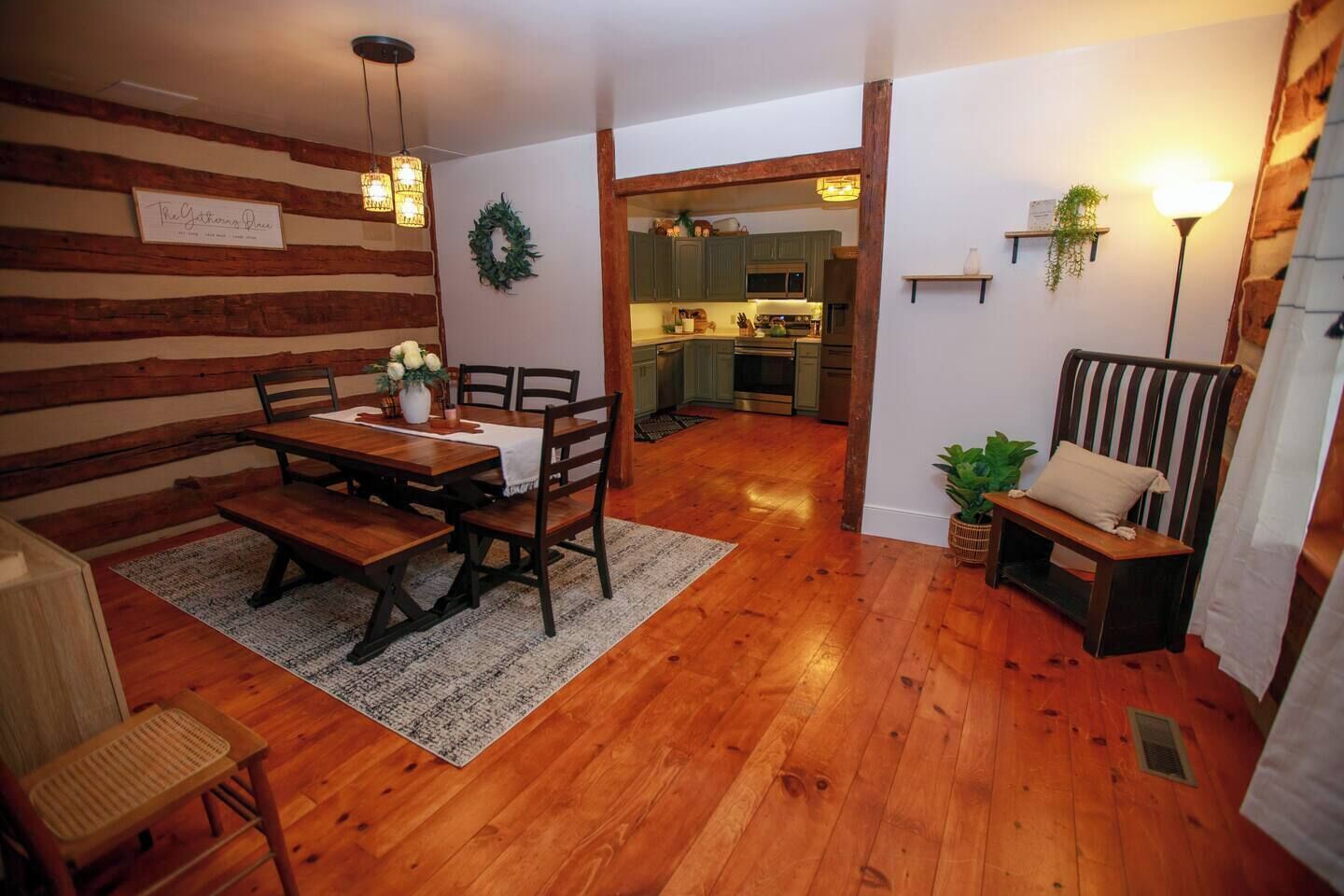 Un coin repas chaleureux avec une table et des chaises en bois, un tapis et un banc agrémenté de coussins.