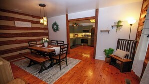 Un comedor acogedor con una mesa y sillas de madera, una alfombra y un banco con cojines.