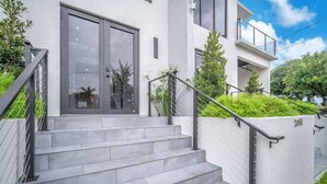 A modern building with a staircase leading to a glass door entrance, surrounded by greenery. - Miami Palm Villas - Family - Entire 8BR-6BA (Miami)