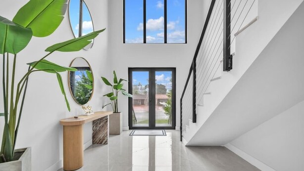 A modern interior with a polished floor, a wooden console table, and large green plants. - Miami Palm Villas - Family - Entire 8BR-6BA (Miami)