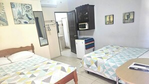 Una habitación con dos camas, una mesita, un microondas y un armario.
