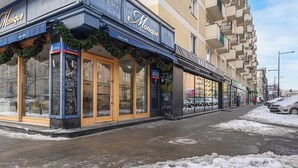 Un immeuble avec un commerce au rez-de-chaussée appelé « Monique » et, de l’autre côté de la rue, une enseigne indiquant « Bar Mleczny ».