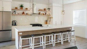 A modern kitchen with a large island, bar stools, and a built-in stove. - New Luxury 3-bedroom Cabin in Big Bear Lake with Hot tub,EV Charger,Pool Table (Big Bear Lake)