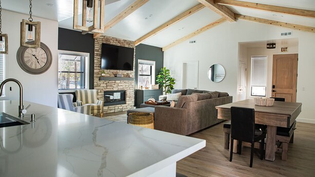 A spacious living area with a stone fireplace, a large TV, and a dining table with chairs. - New Luxury 3-bedroom Cabin in Big Bear Lake with Hot tub,EV Charger,Pool Table (Big Bear Lake)