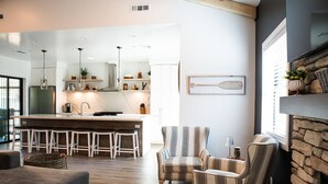 A modern kitchen with bar stools, a striped armchair, and a fireplace. - New Luxury 3-bedroom Cabin in Big Bear Lake with Hot tub,EV Charger,Pool Table (Big Bear Lake)