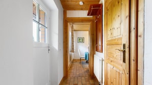 A narrow hallway with wooden doors and a tiled floor.