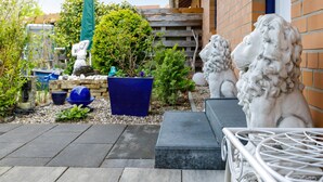 A garden with statues, a blue planter, and a white metal chair.