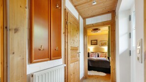 A hallway with wooden doors, a radiator, a bed with floral bedding, and a tiled floor.