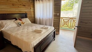A wooden room with a bed, a ceiling fan, and a view of a balcony. - 3-bedroom villa in welcoming Puerto Plata with AC and Fans (puerto plata)