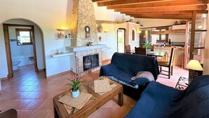 A living room with a fireplace, blue sofa, wooden coffee table, and a stone wall. - Country House 'Ca'n Jutger' with Private Pool, Private Terrace and Wi-Fi (Artà)