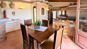 A rustic kitchen with a stone archway, wooden ceiling beams, and a dining area with a table and chairs. - Country House 'Ca'n Jutger' with Private Pool, Private Terrace and Wi-Fi (Artà)