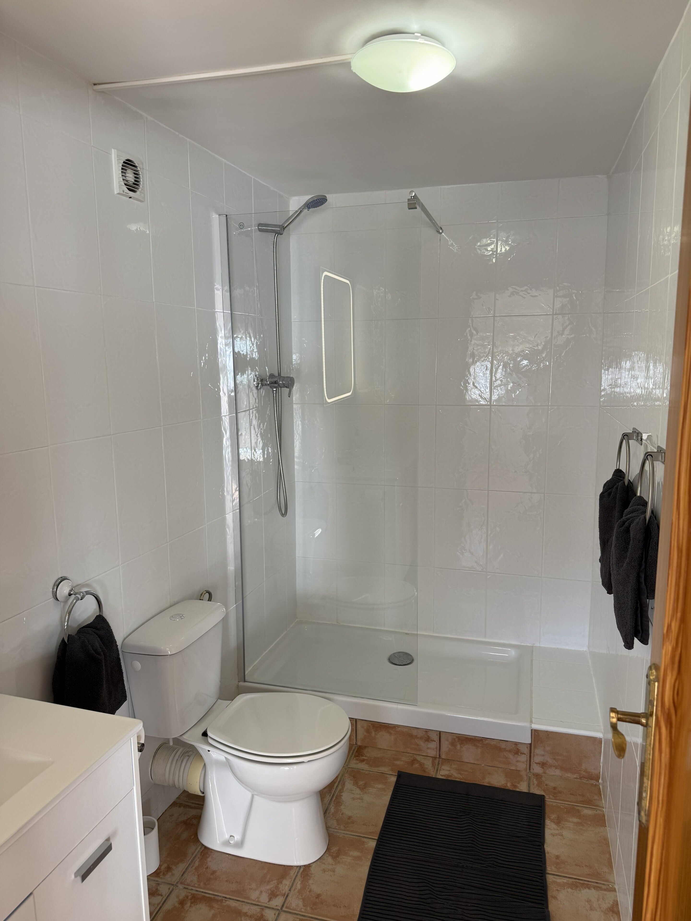 A modern bathroom with a glass-enclosed shower, a toilet, and a bathtub.