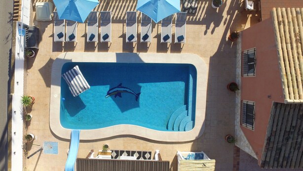 An aerial view of a swimming pool with lounge chairs and umbrellas, surrounded by a tiled patio area. - Luxury family villa with private saltwater pool & casita near Alicante (Busot)