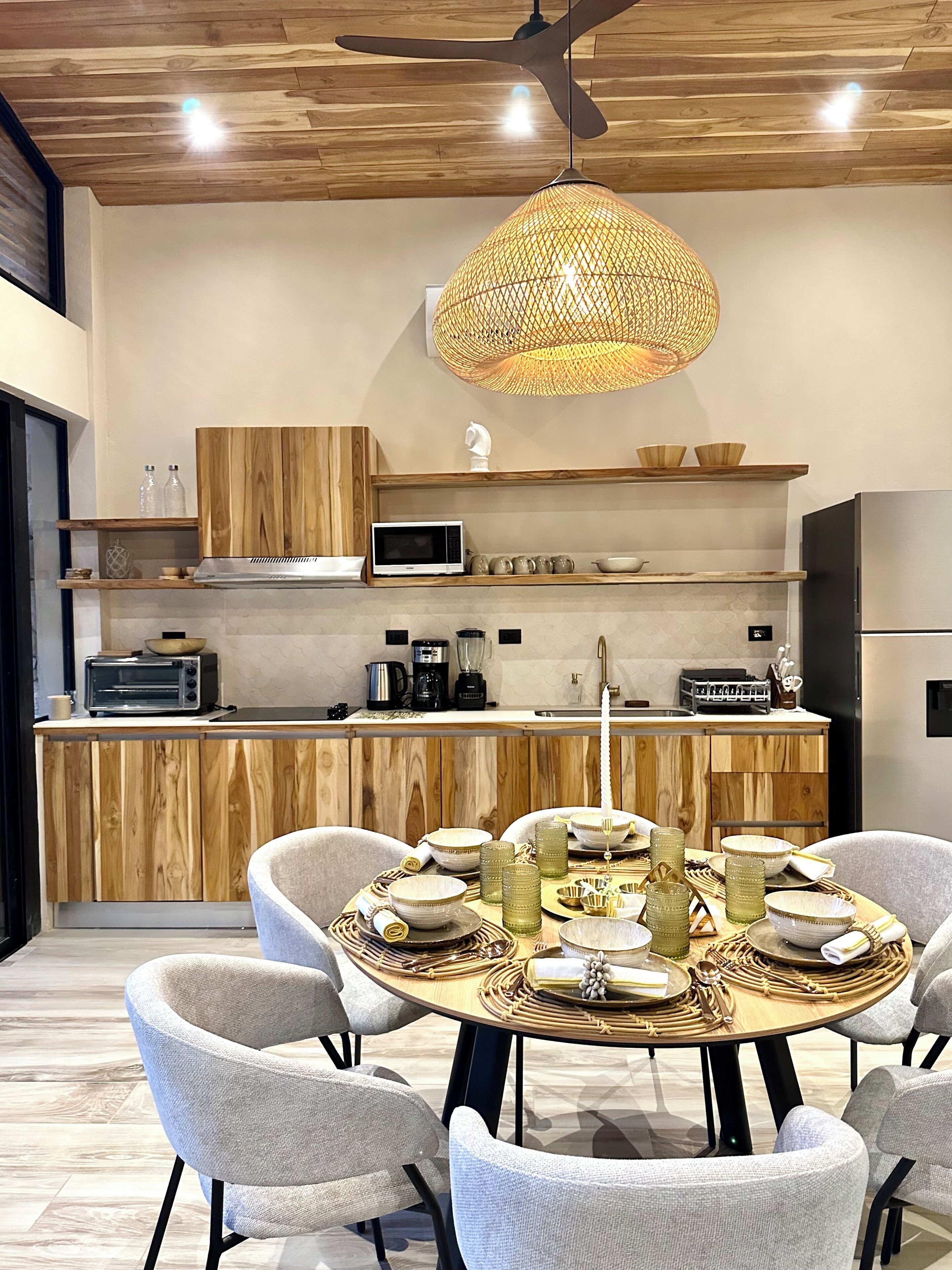 A modern kitchen with wooden cabinets, a microwave, and a dining area with a round table and chairs.