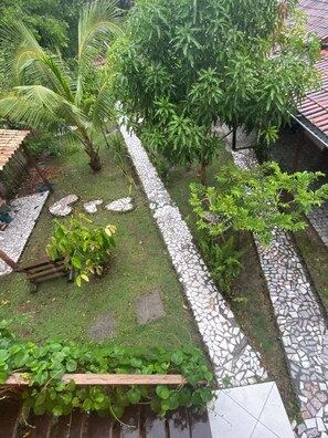 Un jardín con un camino empedrado, diversas plantas y un banco de madera.