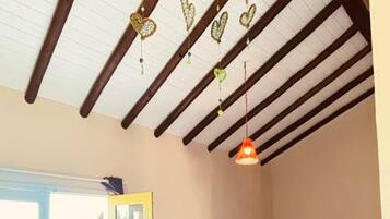 A room with a bed, a table, a hanging heart decoration, and a door leading outside.