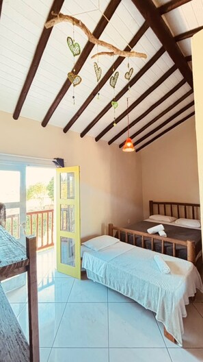 Une pièce comprenant un lit, une table, un cœur décoratif suspendu et une porte donnant sur l’extérieur.