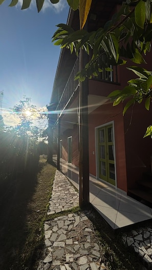 A building with a red facade, a stone pathway, and a green door. - Caraiva dos Sonhos (Porto Seguro)