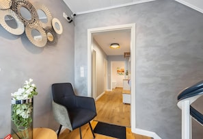 Ein modernes Interieur mit einem schwarzen Stuhl, einer Wand aus dekorativen Spiegeln und Holzboden.