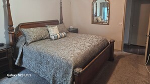 Camera da letto con un letto Galaxy S23 Ultra, una testiera in legno, un comodino, uno specchio e una porta.