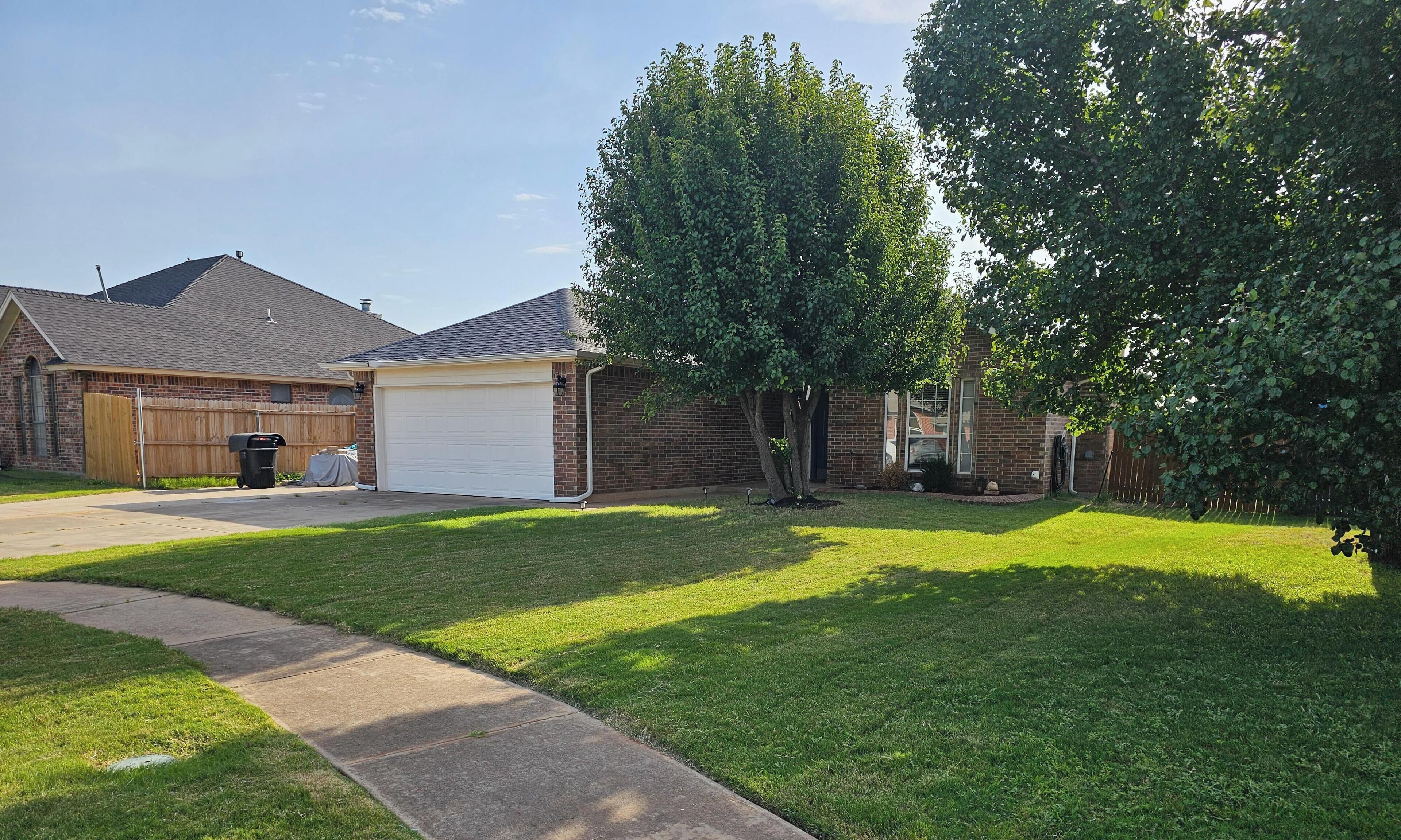 A residential property with a garage, a covered patio, and a well-maintained lawn.