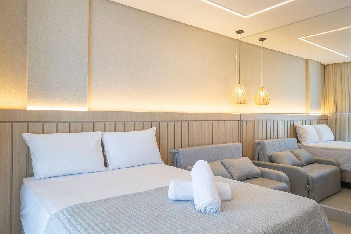 A modern hotel room with a large bed, two sofas, a small table, and a mirror.
