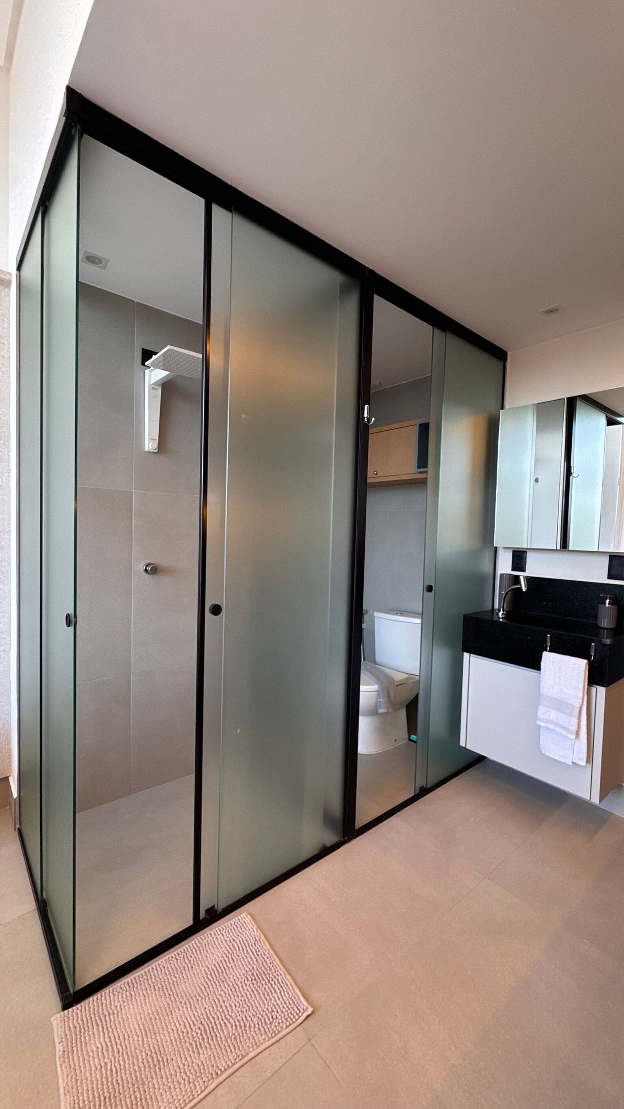 A modern bathroom with a glass partition, a toilet, and a sink with a towel.