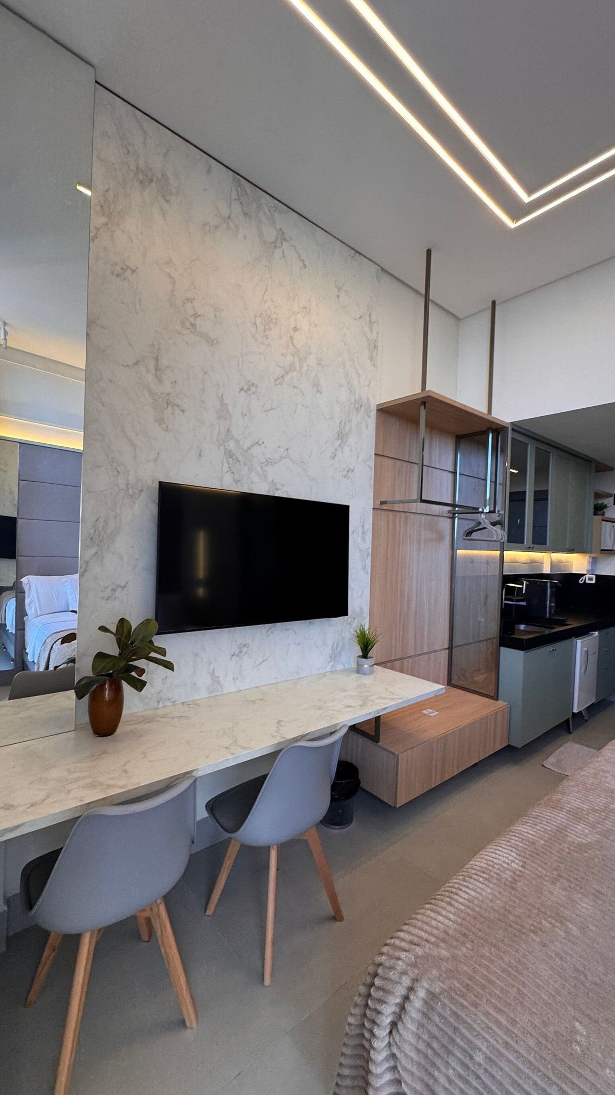 A modern kitchen with a built-in TV, marble backsplash, and wooden cabinets.