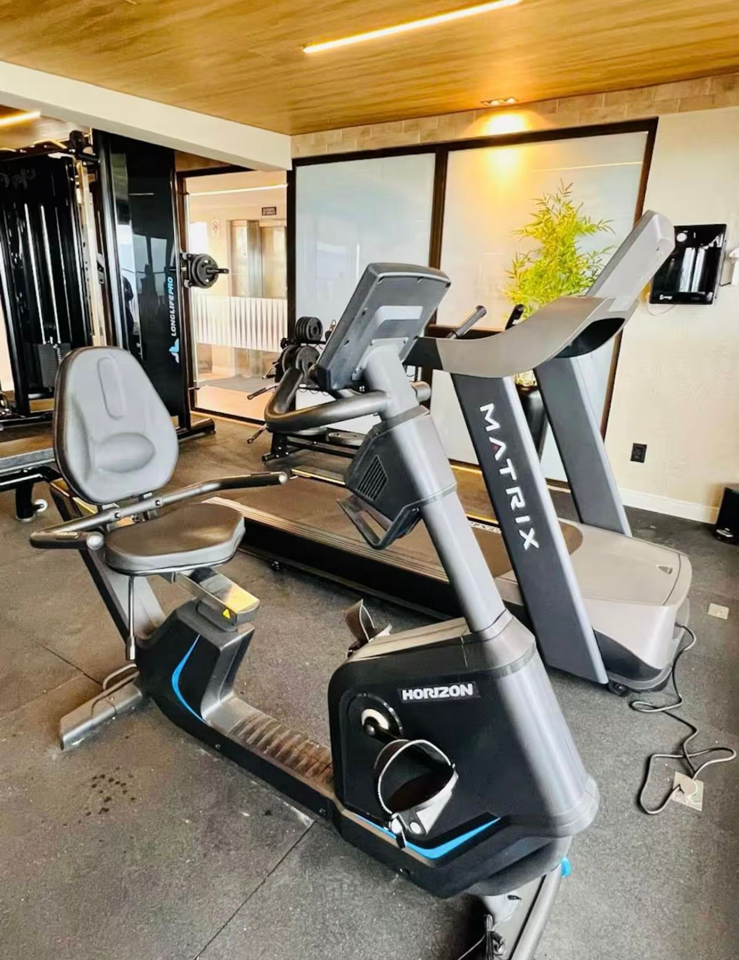 Un gimnasio con bicicletas estáticas, máquinas de pesas y una cinta de correr.
