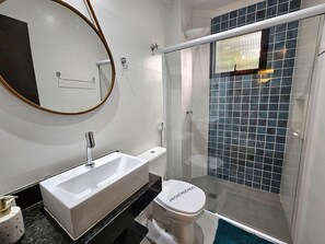 Une salle de bain avec une baignoire blanche, des toilettes et une douche séparée par une paroi en verre.