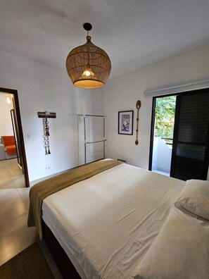 Une chambre avec un grand lit, un luminaire suspendu, un porte-serviettes et une fenêtre donnant sur un beau paysage.
