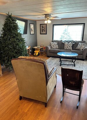 A living room with a large Christmas tree, a sofa set, a coffee table, and a wooden floor. - Soothing 3-bedroom farmhouse with AC on 2 acres just outside of Sergeant Bluff (Salix)