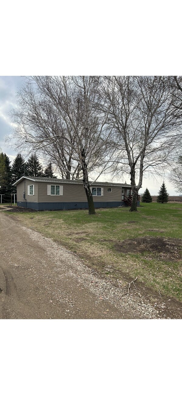 A single-story mobile home with a front yard and a large tree. - Soothing 3-bedroom farmhouse with AC on 2 acres just outside of Sergeant Bluff (Salix)