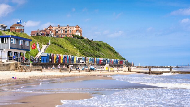 A coastal hotel with a beach view, a staircase leading to the upper levels, and a flag on the building.