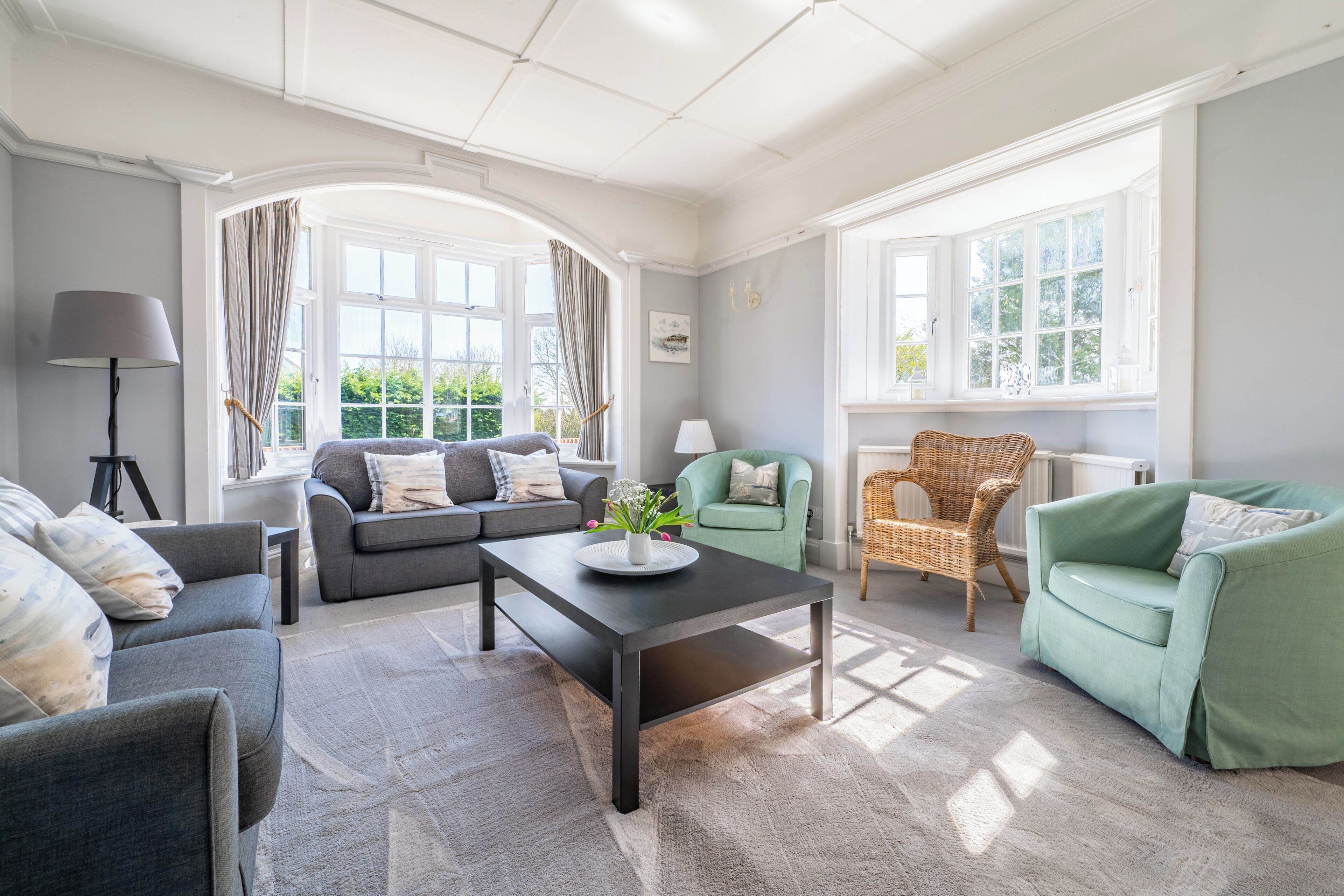 Un salon avec un canapé, des fauteuils, une table basse et une lampe.