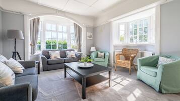 Un salon avec un canapé, des fauteuils, une table basse et une lampe.