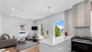 A modern kitchen with white cabinetry, a built-in oven, and a large window offering a view of the outdoors. - Kate's House (GuestHouse) (Walton County)