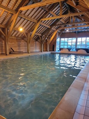 An indoor swimming pool with wooden beams and a tiled floor. - Bright Apartment for 4 - Balcony - Parking - Swimming Pool (Saint-Sorlin-d´Arves)