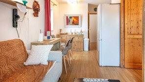 A cozy living room with a sofa, a small table, and a kitchen area in the background. - Bright Apartment for 4 - Balcony - Parking - Swimming Pool (Saint-Sorlin-d´Arves)